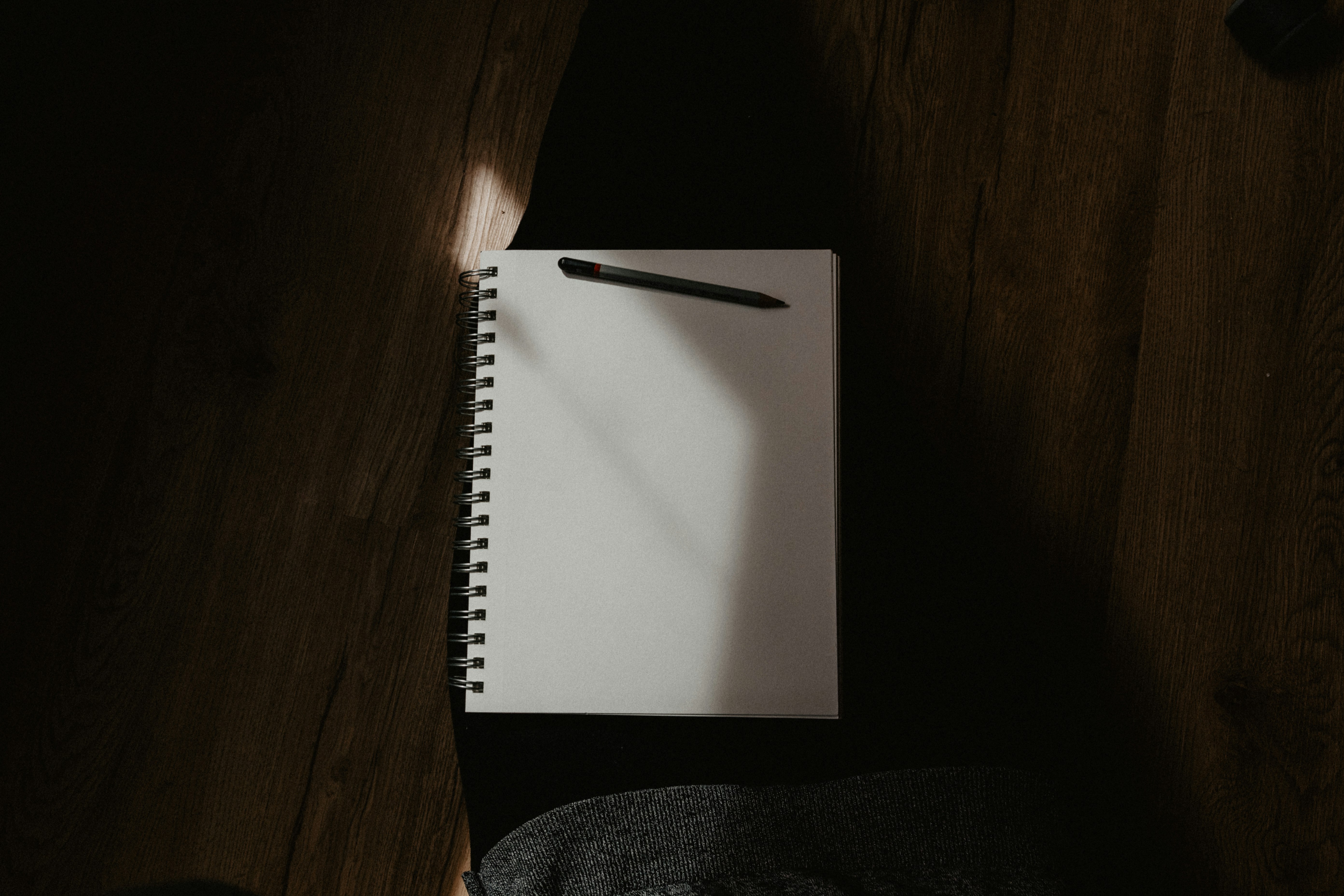 white spiral notebook on black textile